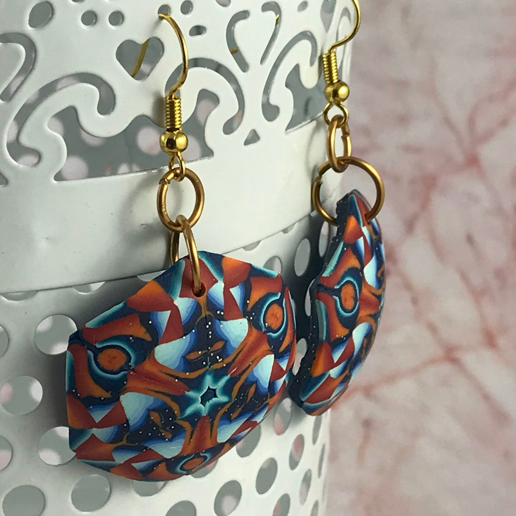 Side angle view of handmade polymer clay geometric drop earrings showing thickness, smooth finish and gold hook connectors.