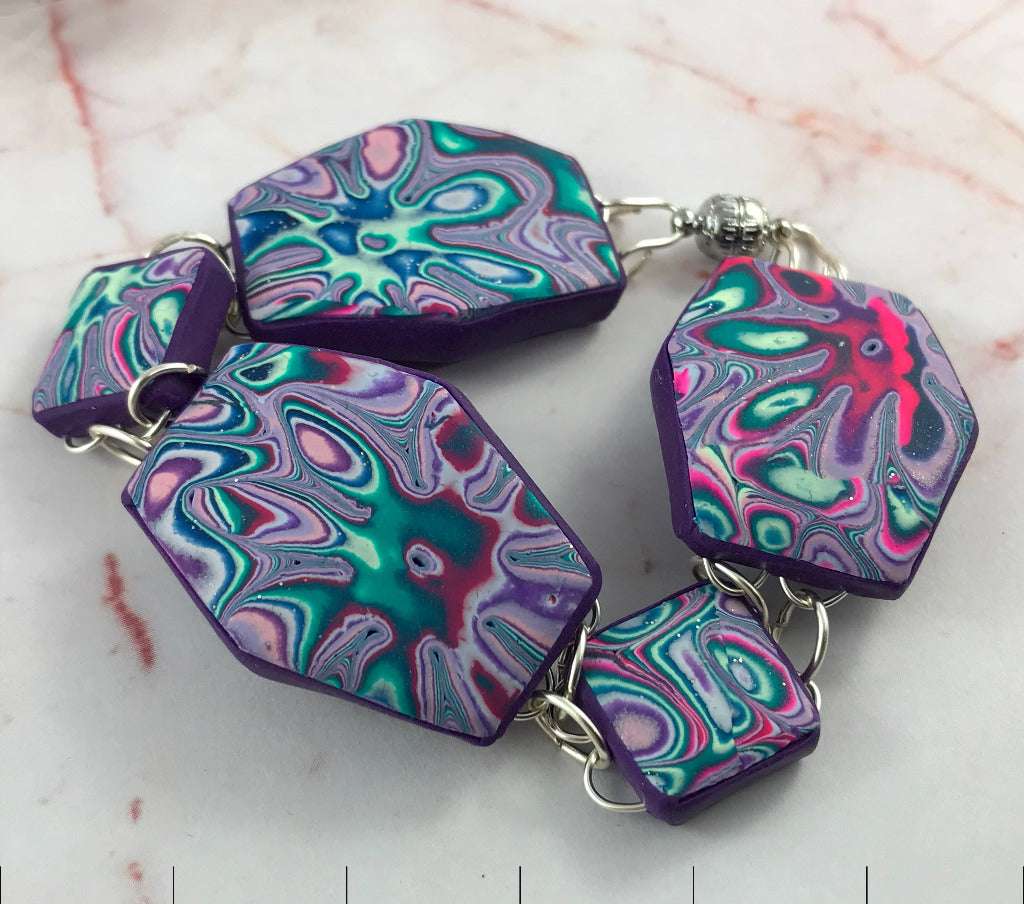 Close-up of handmade geometric polymer clay bracelet in purple, teal and pink marbled swirl design with silver links and artisan finish, Australian handmade jewellery