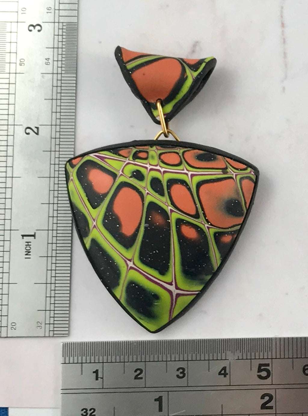 Handmade polymer clay pendant necklace with bold orange, green and black abstract pattern, lightweight air-filled curved design, unique artisan jewellery Australia
