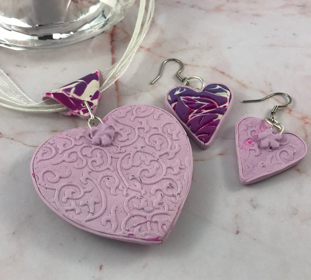 Back view of large pink heart pendant and matching earrings showing decorative patterned finish.