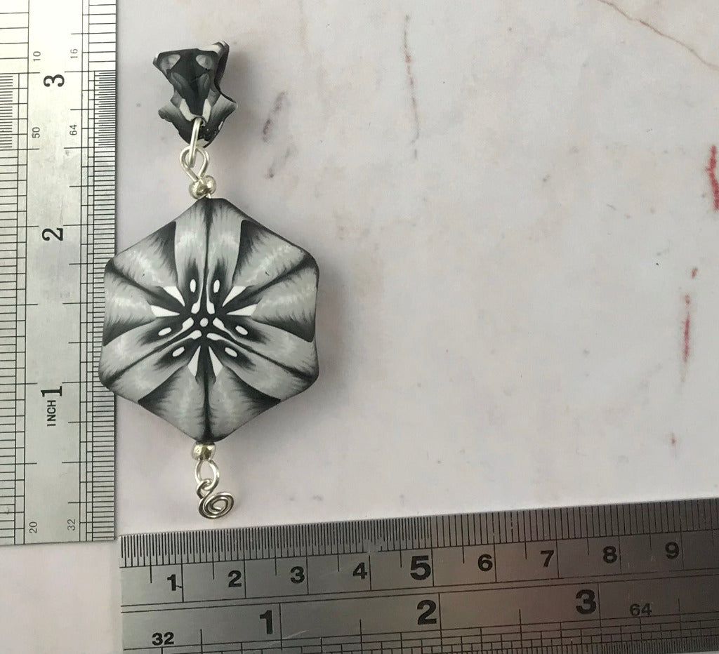 Close-up of handmade black white grey polymer clay pendant necklace with abstract floral geometric pattern, one of a kind artisan jewellery Australia