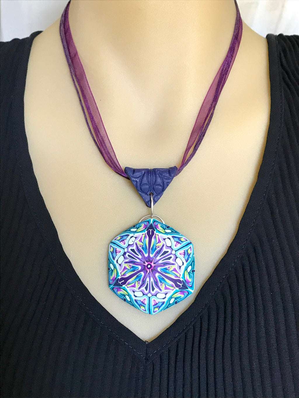 Pastel floral statement pendant necklace displayed on silver neck ring with blue, purple and lilac abstract design