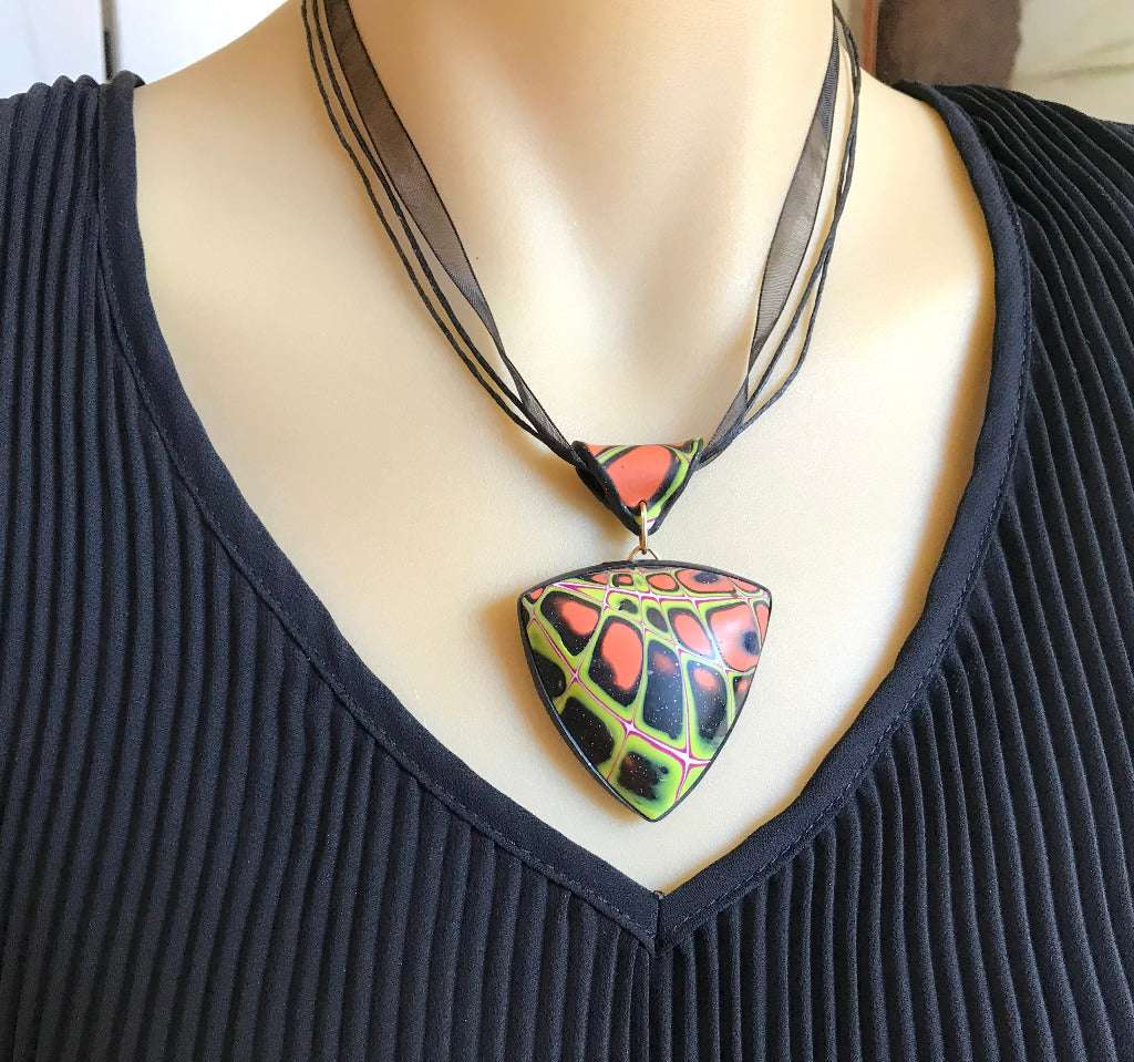 Handmade polymer clay pendant and earrings set with bold abstract pattern, lightweight air-filled design in orange green and black, artisan jewellery Australia