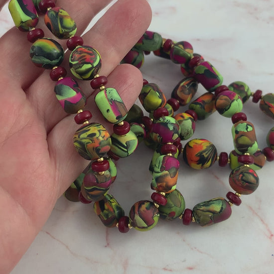 video showing long hand-crafted polymer clay necklace being picked up to show length