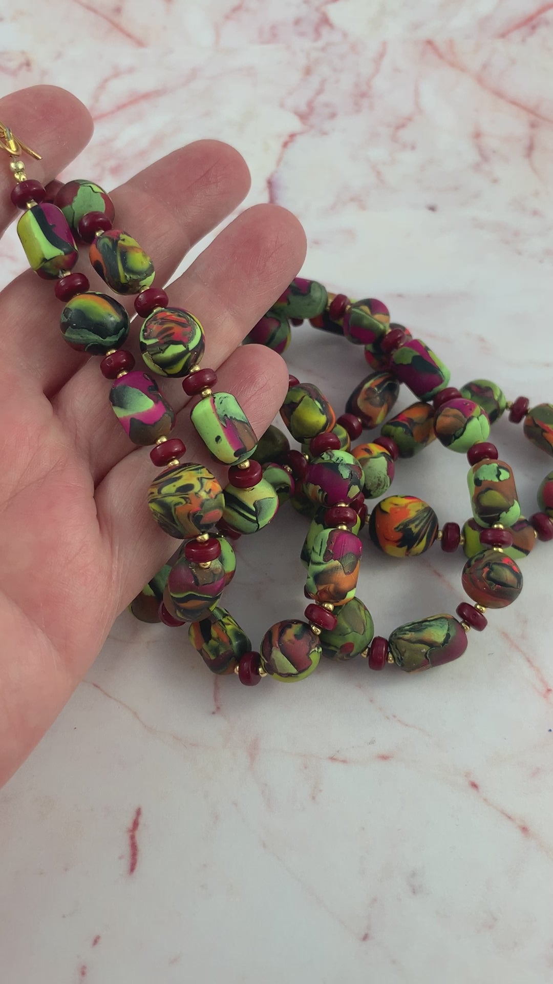 video showing long hand-crafted polymer clay necklace being picked up to show length