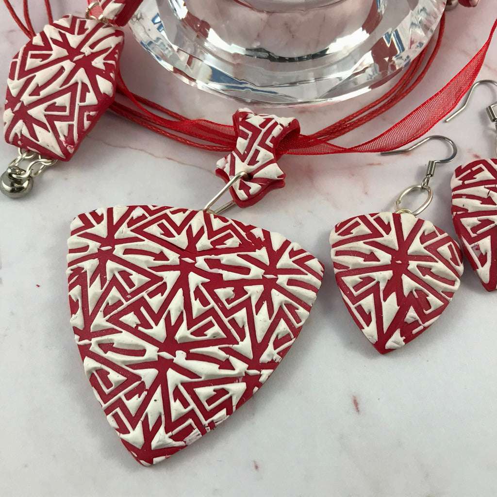 Close-up of handmade red and white jewellery set showing curved shape and prominent textured surface.