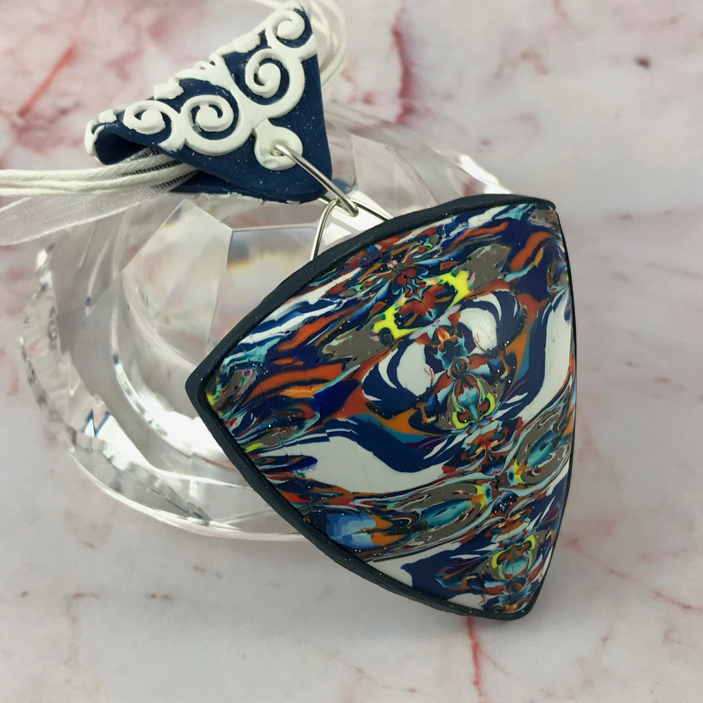 Close side angle of blue and white abstract pendant showing handcrafted depth and curvature.