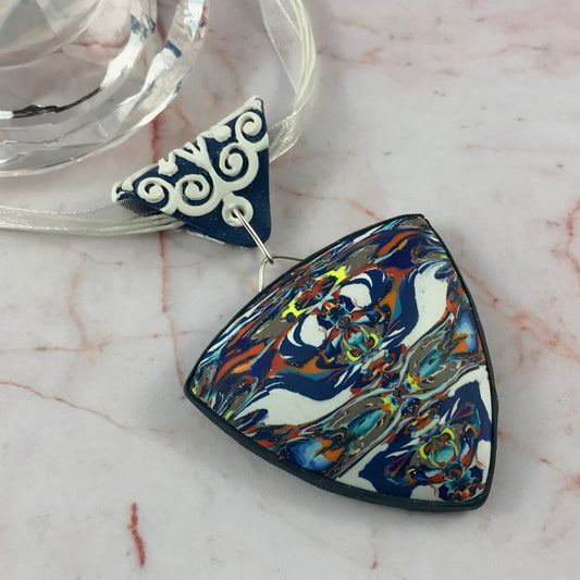 Bold blue and white abstract feature pendant in handmade polymer clay with marbled coastal-inspired design.