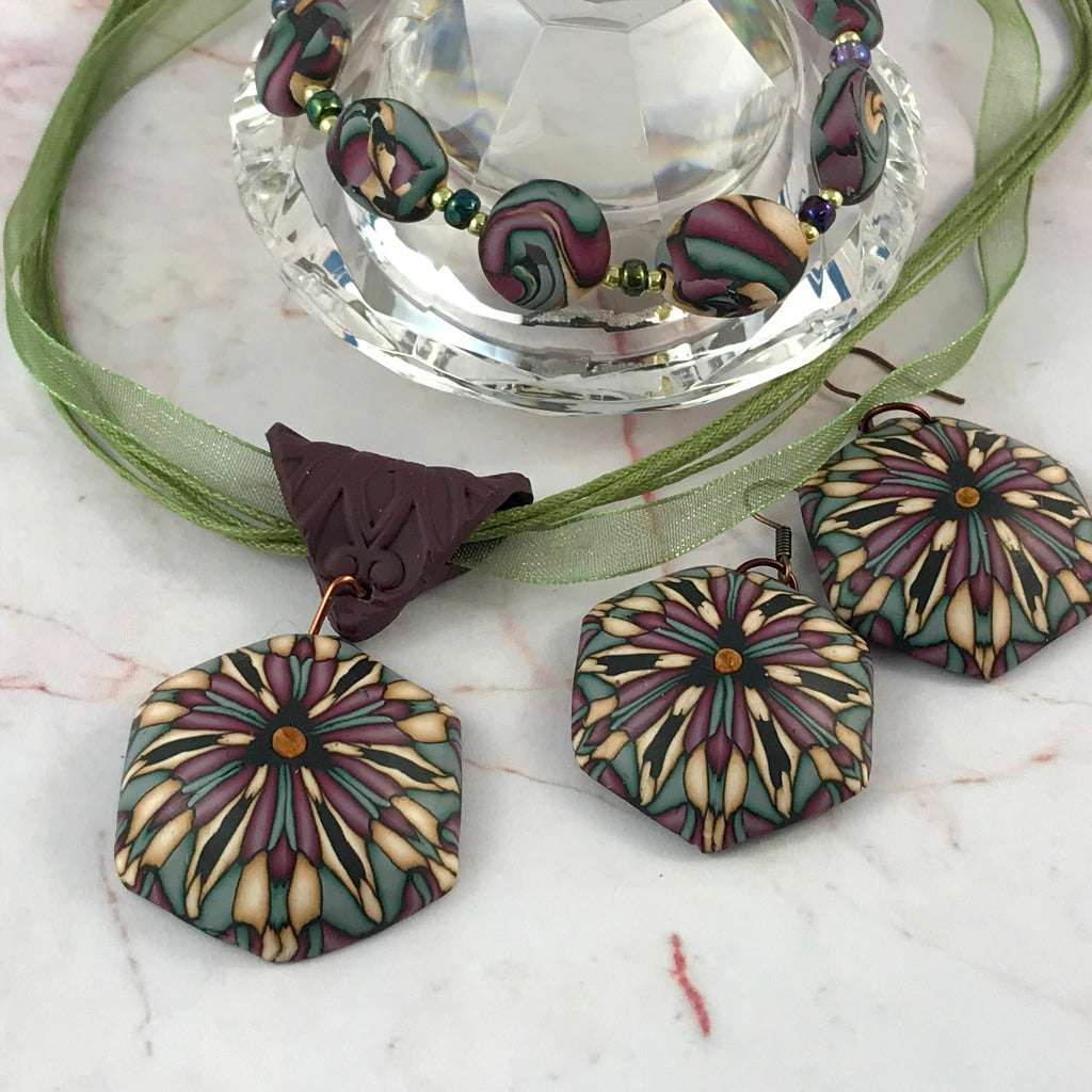 Rennique handmade deep red geometric polymer clay pendant styled on green ribbon cord, abstract artisan necklace with muted complementary accents