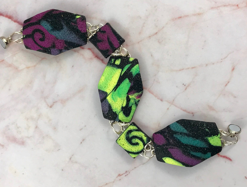 Rennique geometric polymer clay bracelet with patchwork textured pattern in purple, lime green, teal and black with magnetic clasp