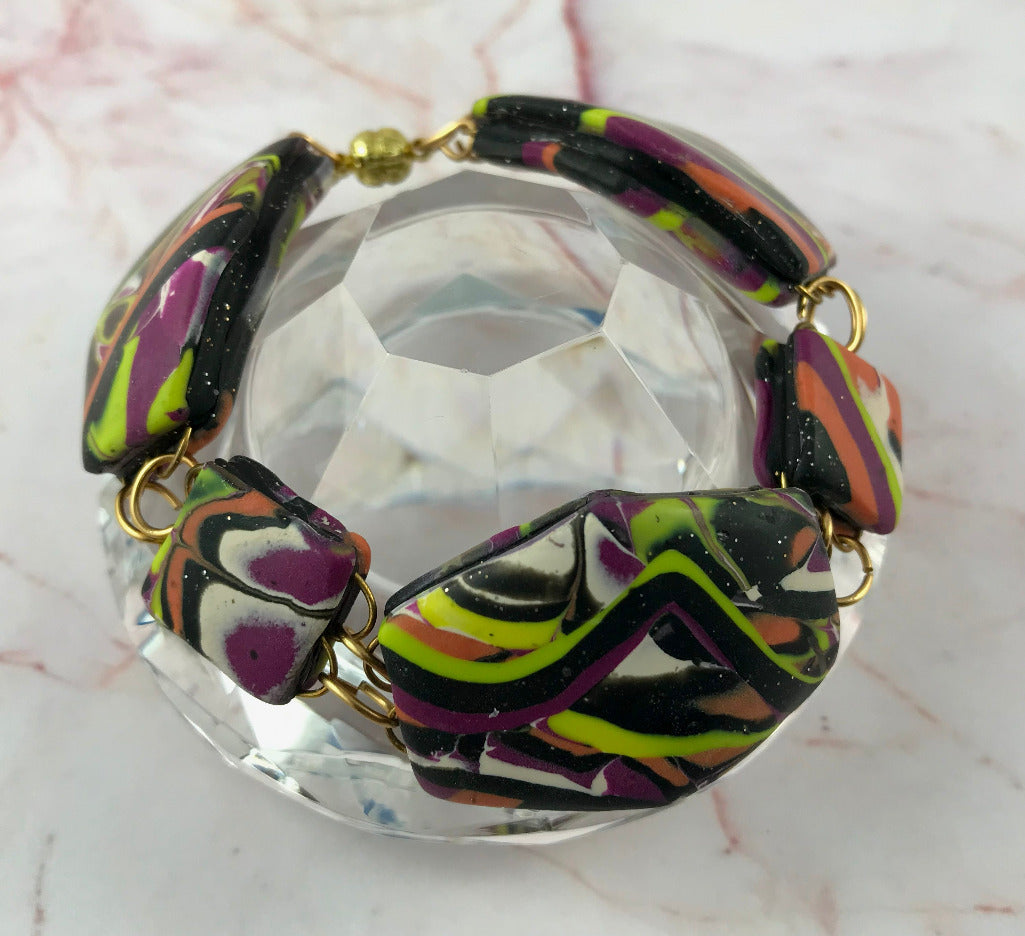 Patchwork bracelet displayed on glass stand showing curved handmade design.