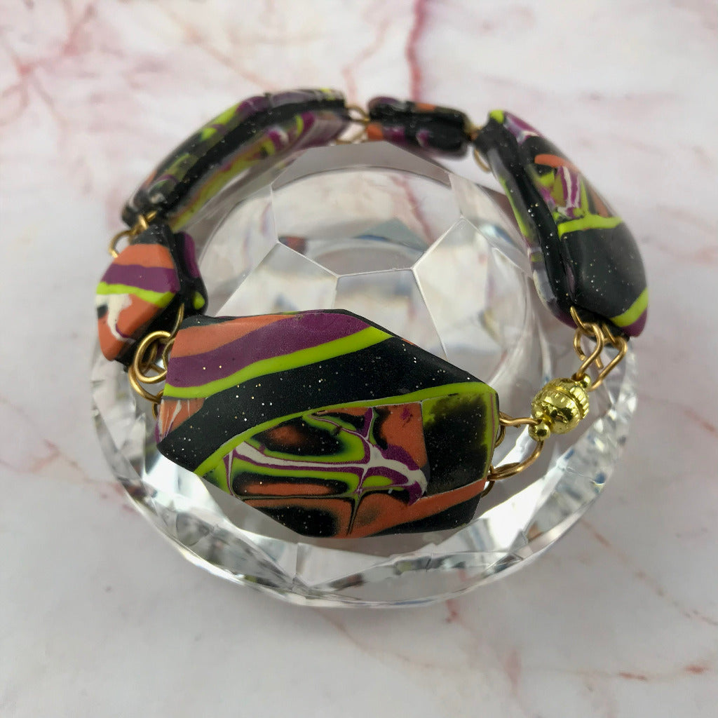 Close-up of patchwork bracelet on glass with handcrafted wire and metal clasp detail.