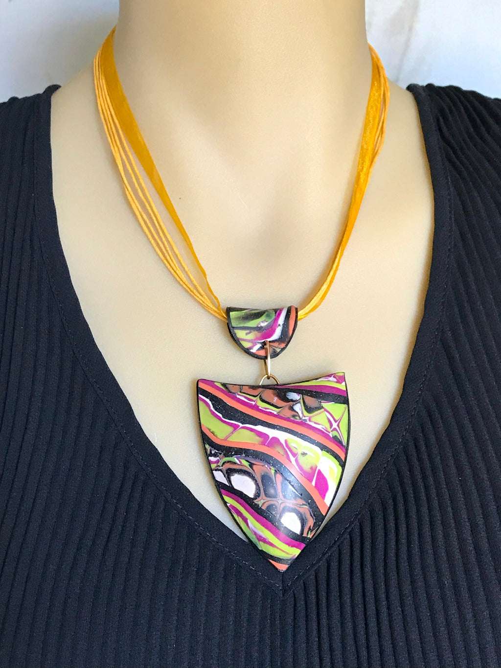 Close-up of patchwork pendant necklace worn on mannequin.