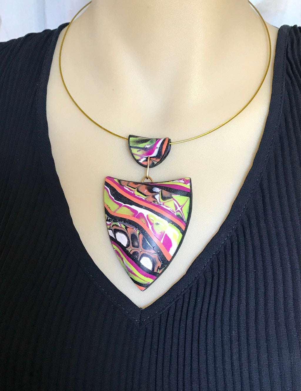Side close-up of abstract patchwork pendant worn on mannequin.