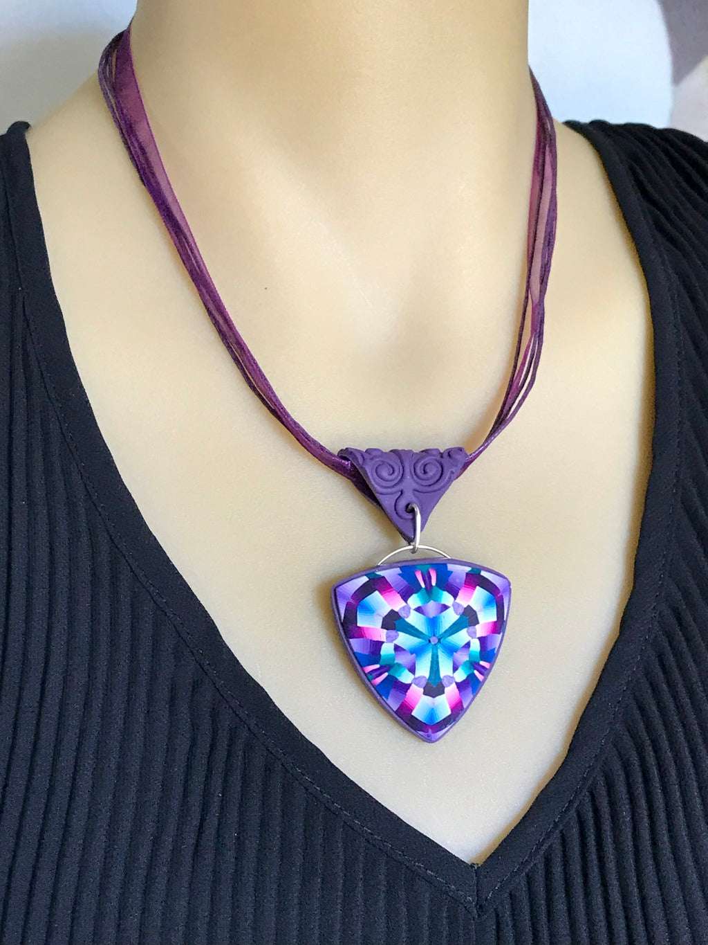 Close-up of pink and purple statement pendant necklace worn on mannequin for styling reference.