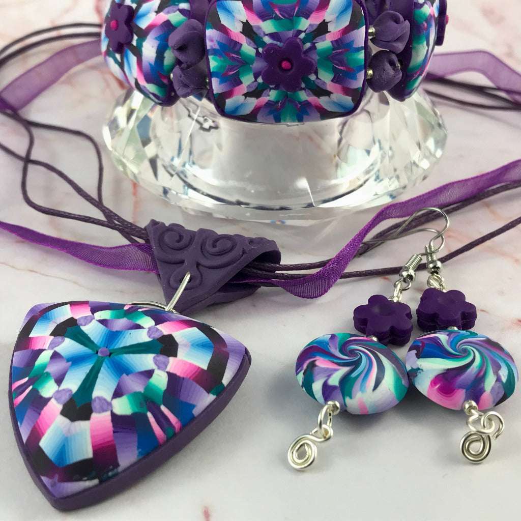 Detailed close-up of pink and purple polymer clay pendant necklace with matching earrings.