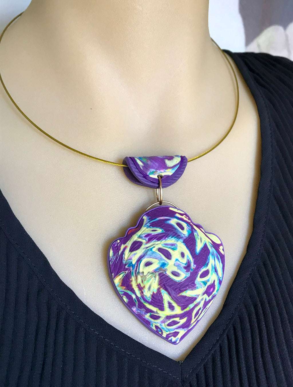 Close-up of Rennique handcrafted purple heart swirl polymer clay pendant with curved air-filled lightweight design and textured surface