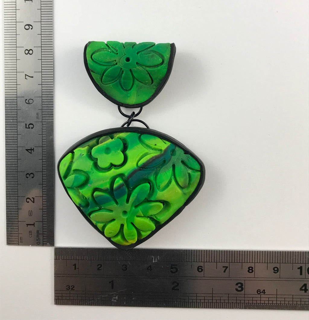 Rennique spring green carved floral polymer clay statement pendant with black edging and domed texture shown with size ruler