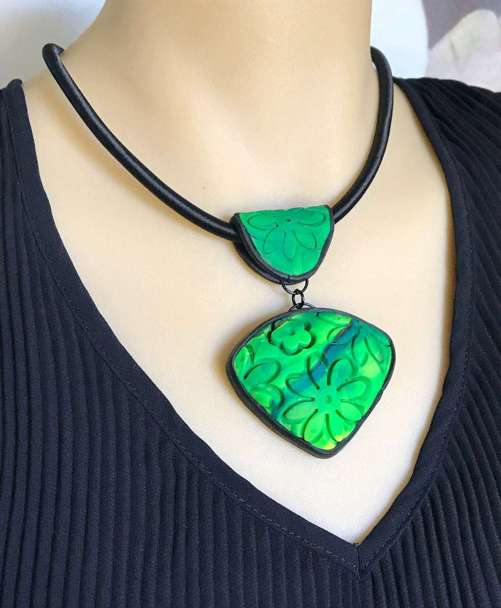 Rennique spring green carved floral polymer clay pendant necklace displayed on black cord worn on mannequin