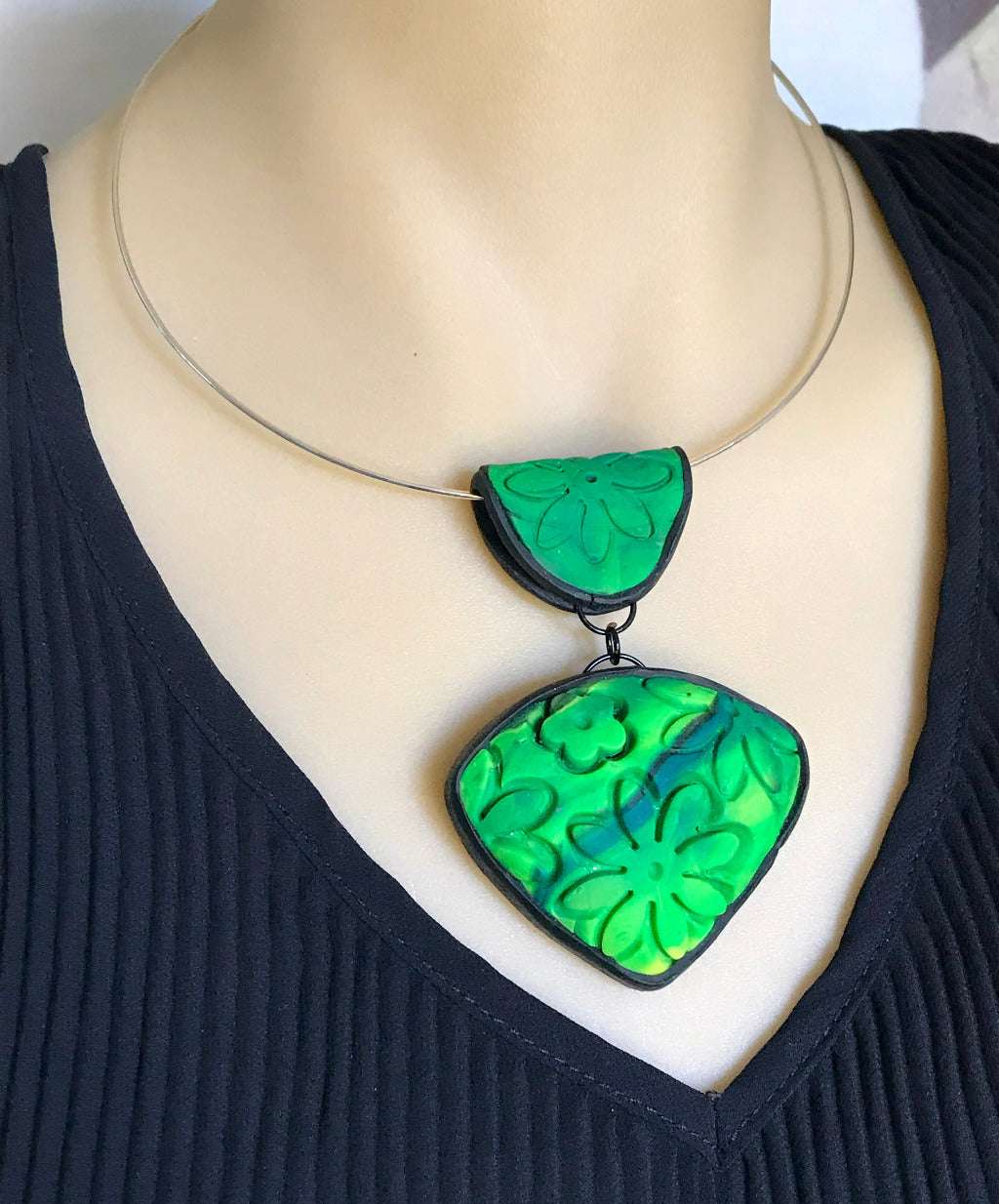 Rennique spring green floral carved polymer clay statement pendant displayed on silver neck ring worn on mannequin