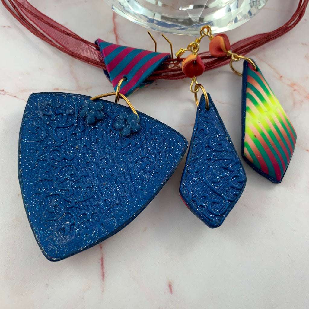 Back view of Rennique handcrafted polymer clay pendant and earrings set showing textured navy blue glitter finish and embossed swirl detailing.