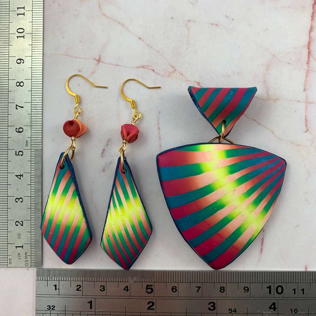 Rennique wearable art pendant and matching earrings shown with ruler for size reference, handcrafted polymer clay in vibrant striped pink, teal, and lime design.
