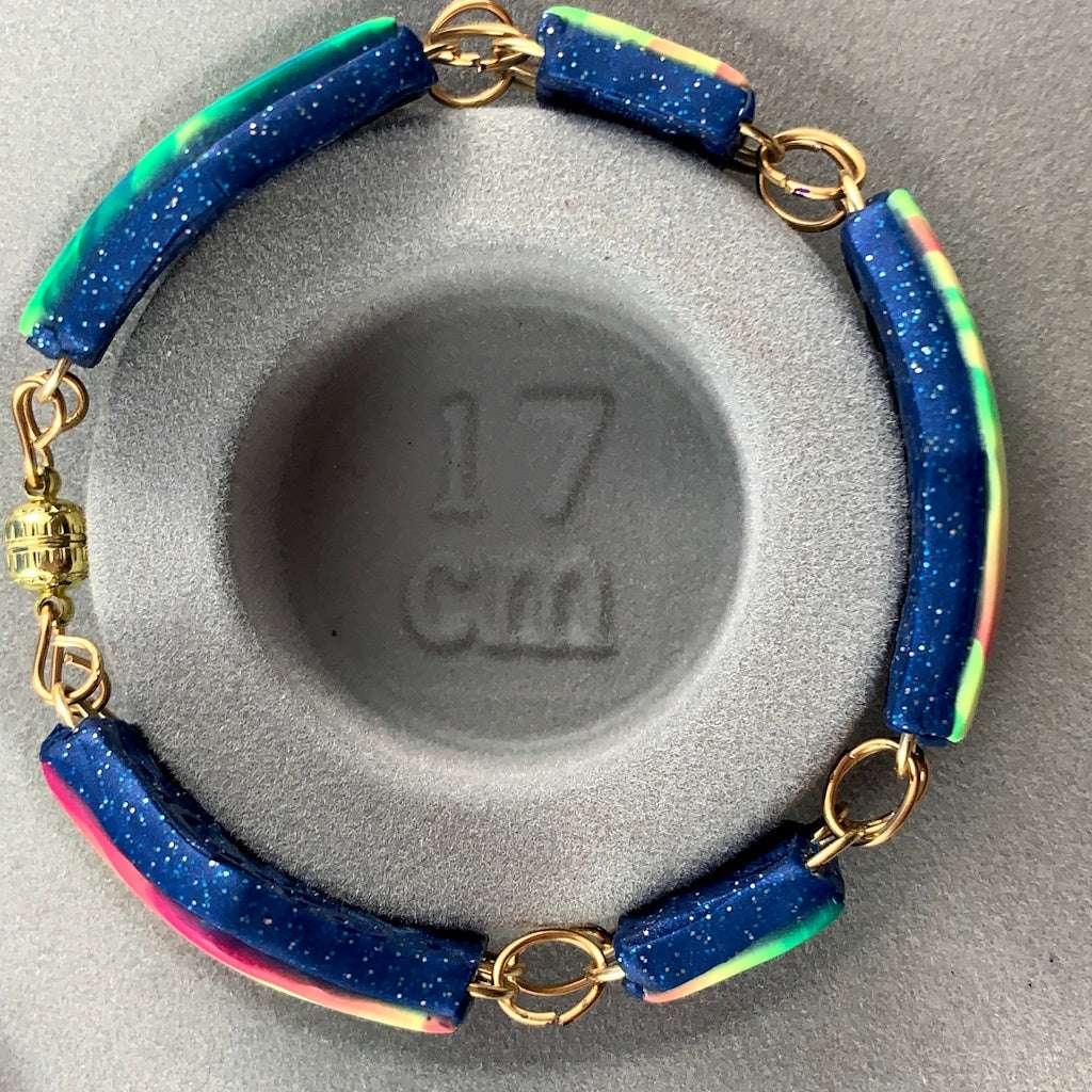 Handmade Rennique matching link bracelet with navy glitter edge and vibrant pink, teal, aqua and cream striped polymer clay panels with gold links.