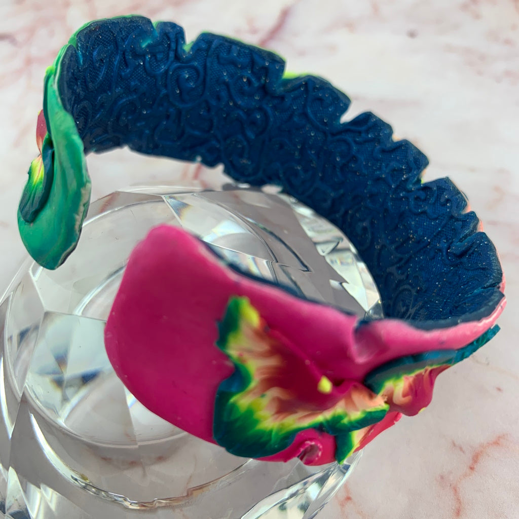 Side view of Rennique one-of-a-kind tropical theme cuff bracelet featuring sculpted floral petal layers in pink, green and blue tones.