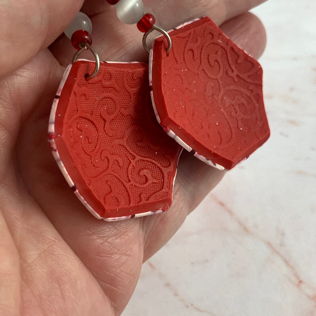 Back view of Rennique handmade red and white polymer clay statement earrings with embossed textured finish and artisan detailing.