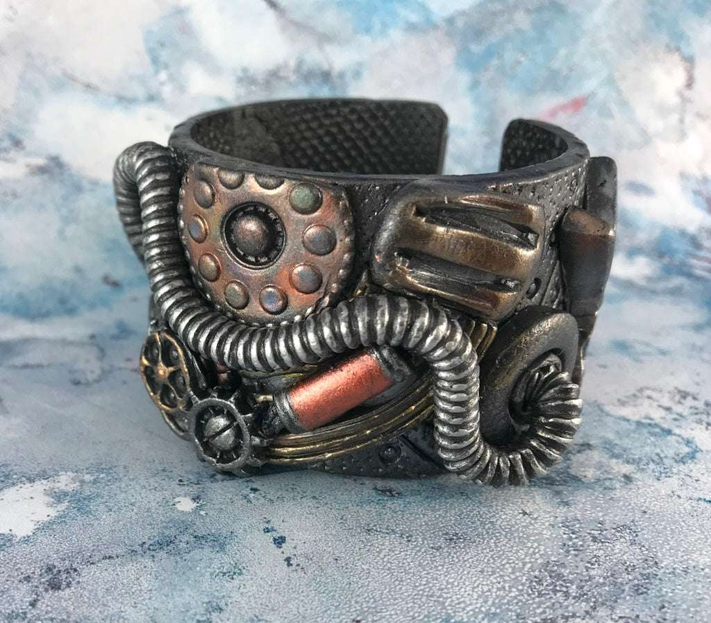 Rennique Studio one-of-a-kind steampunk cuff bracelet featuring industrial gears, coils, and metallic textures in oxidised copper, bronze, and gunmetal polymer clay wearable art.