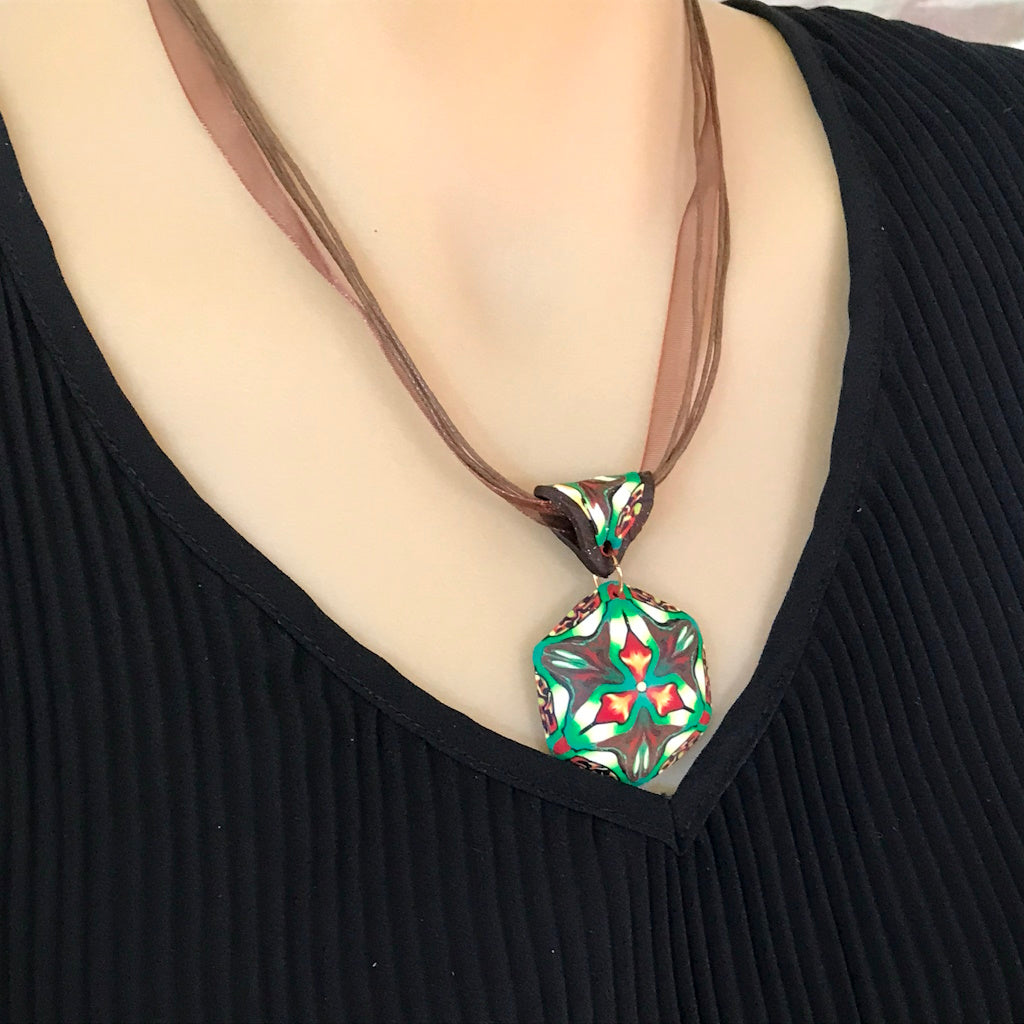 Rennique one-of-a-kind butterfly-inspired polymer clay drop earrings in tropical green, black, cream, and orange with gold infinity hooks.