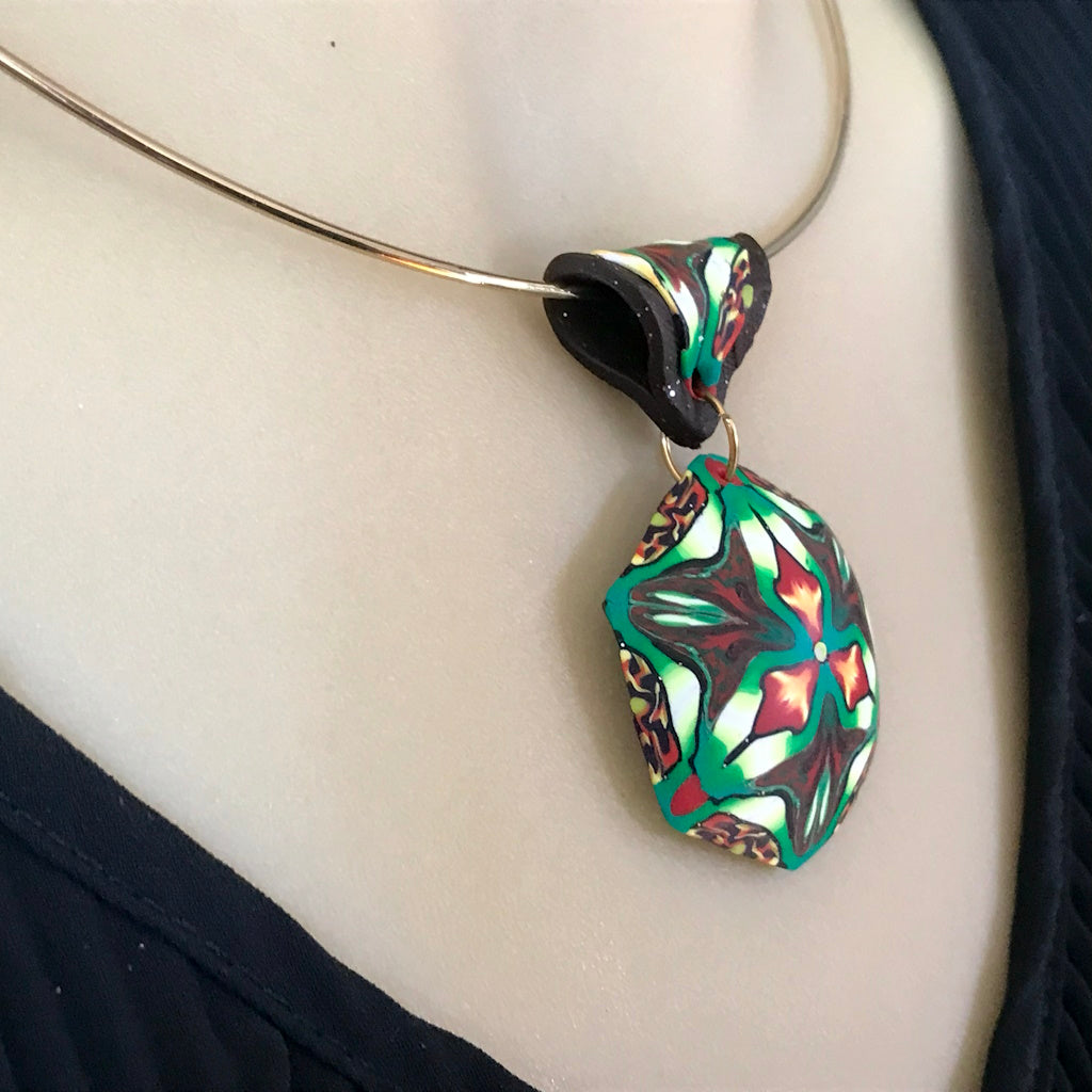 Rennique statement polymer clay pendant necklace worn on silver choker featuring tropical kaleidoscope floral design.
