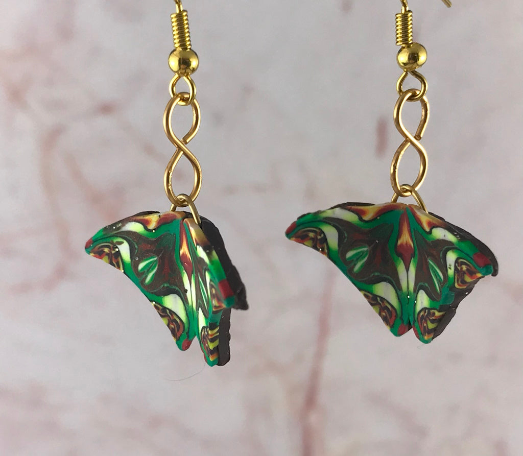 Close-up of Rennique handmade tropical drop earrings featuring butterfly wing design in green, black, cream, and fiery orange tones.