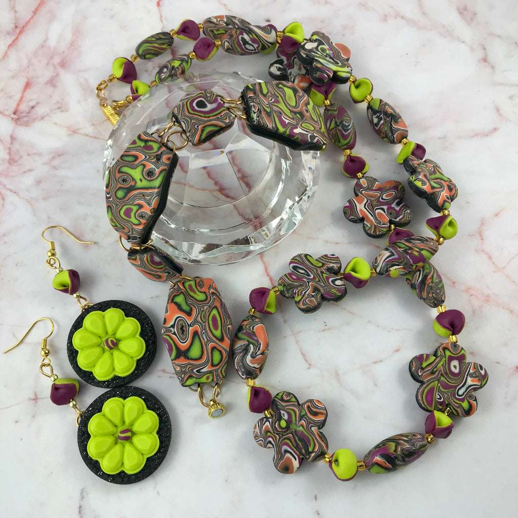 Complete handmade jewellery set flat lay including necklace, bracelet and floral earrings in one-of-a-kind ripple autumn tone polymer clay design.