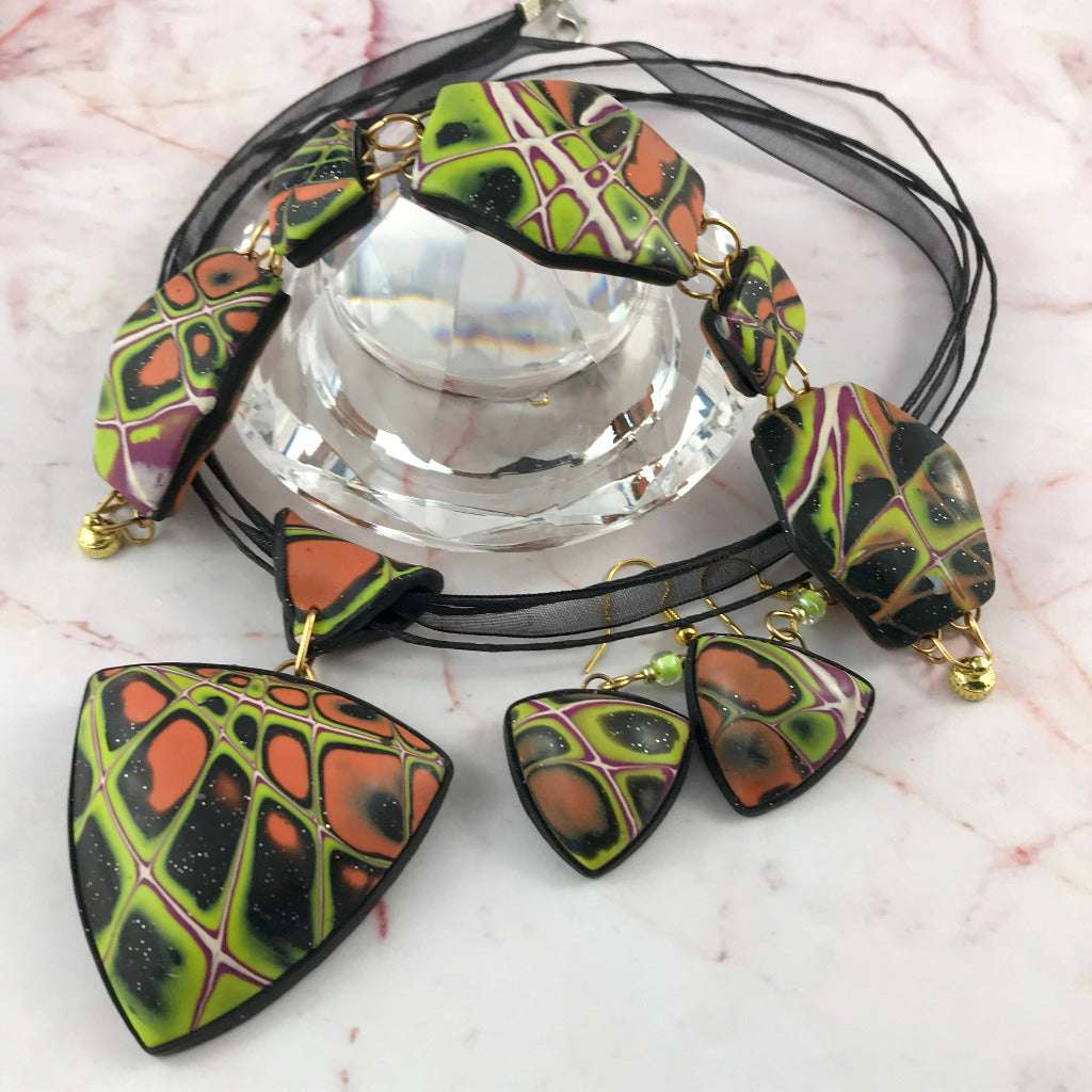 Statement polymer clay pendant necklace worn on black cord, bold orange green abstract design, lightweight artisan jewellery Australia