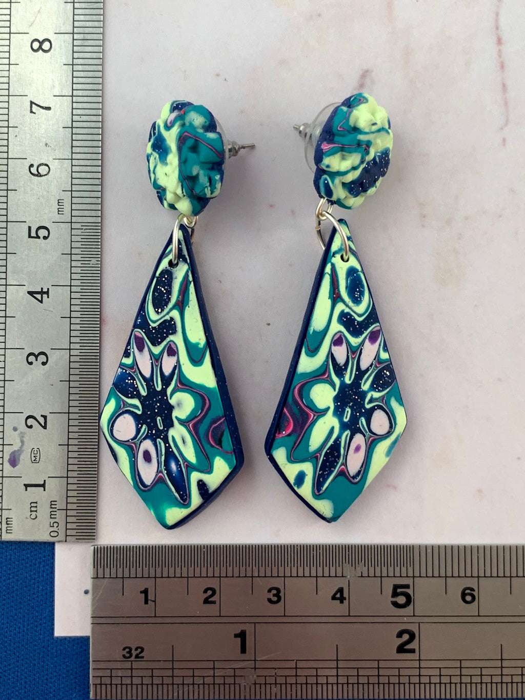 Handmade teal and navy polymer clay earrings shown with ruler for accurate size reference and dimensions.