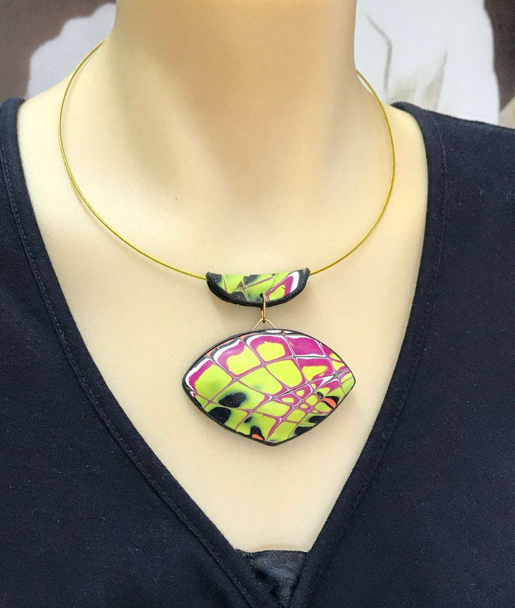 Statement yellow and purple abstract pendant necklace displayed on mannequin bust showing wearable length.