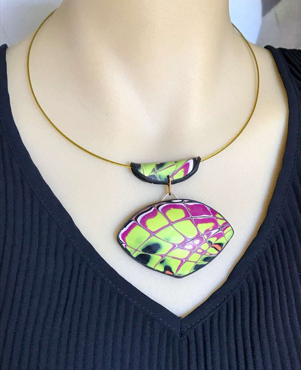 Yellow and purple abstract pendant necklace worn on mannequin showing front drape and fit.
