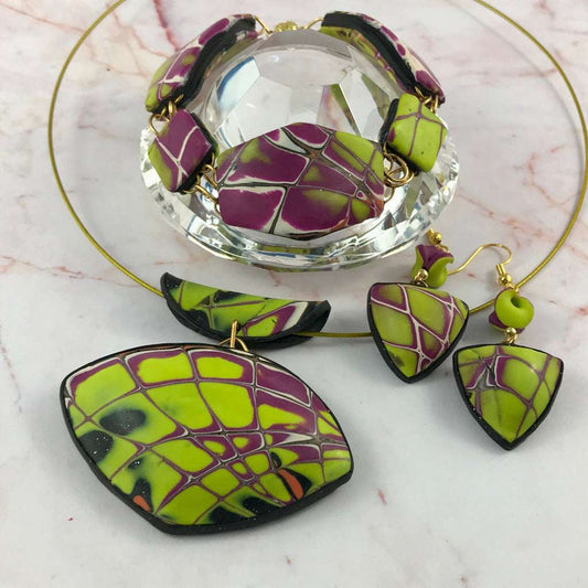 One-of-a-kind yellow and purple modern abstract polymer clay jewellery set featuring pendant, earrings, and bracelet with bold geometric pattern.