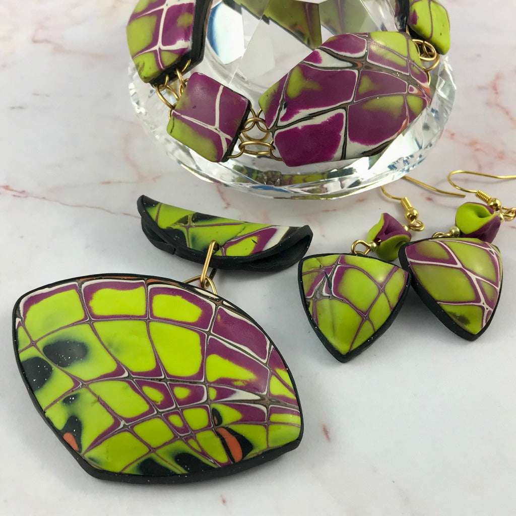 Detailed close-up images of bracelet, pendant, and earrings in yellow and purple abstract polymer clay design.